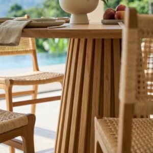 Fluted wooden dining table base with woven chairs in a luxury villa