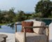 Rustic teak lounge chair with beige cushions and woven backrest on a luxury resort terrace