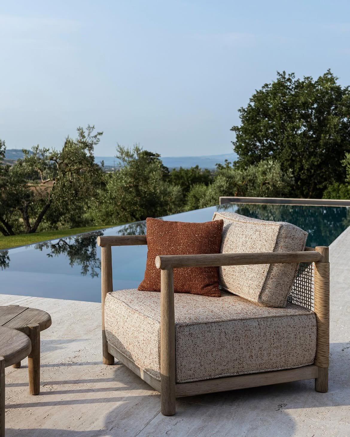 Rustic teak lounge chair with beige cushions and woven backrest on a luxury resort terrace